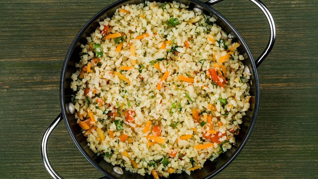 Cauliflower rice with colorful vegetables in a pan.