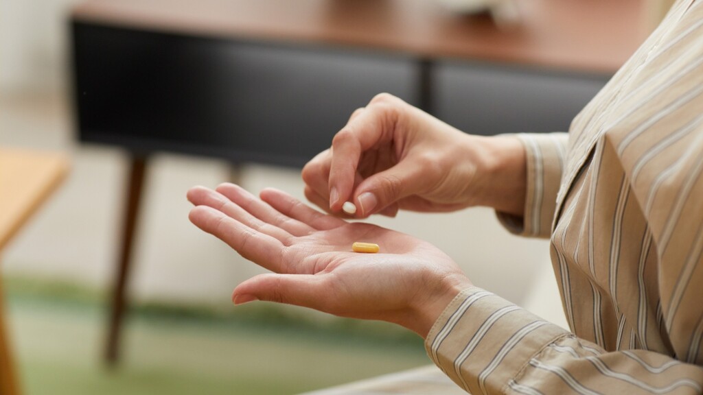 Person taking pills from their hand.