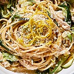Lemon chicken spaghetti with zucchini ribbons, parmesan, and fresh lemon zest in a white bowl.