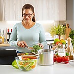 Woman prepping vegetables in a kitchen.