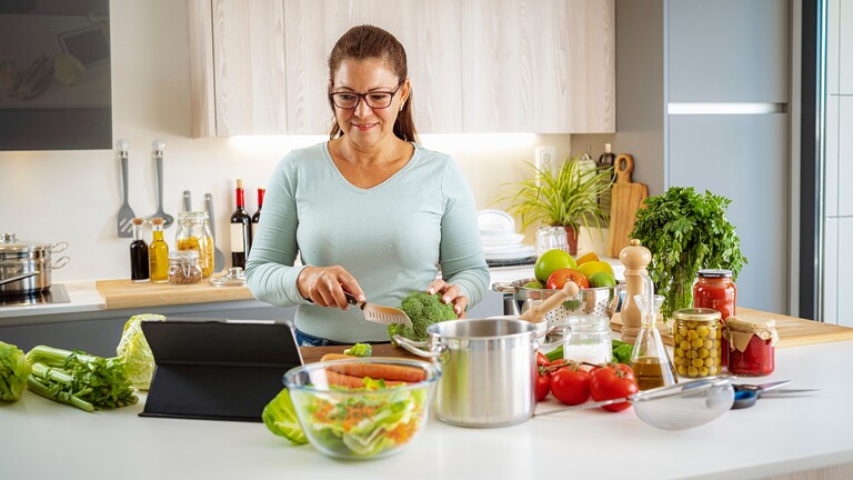 Woman prepping vegetables in a kitchen.