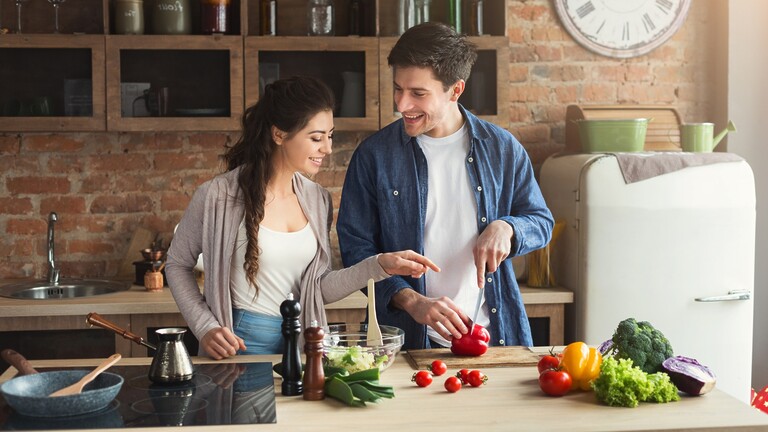 Couple preparing vegetables together in a kitchen.