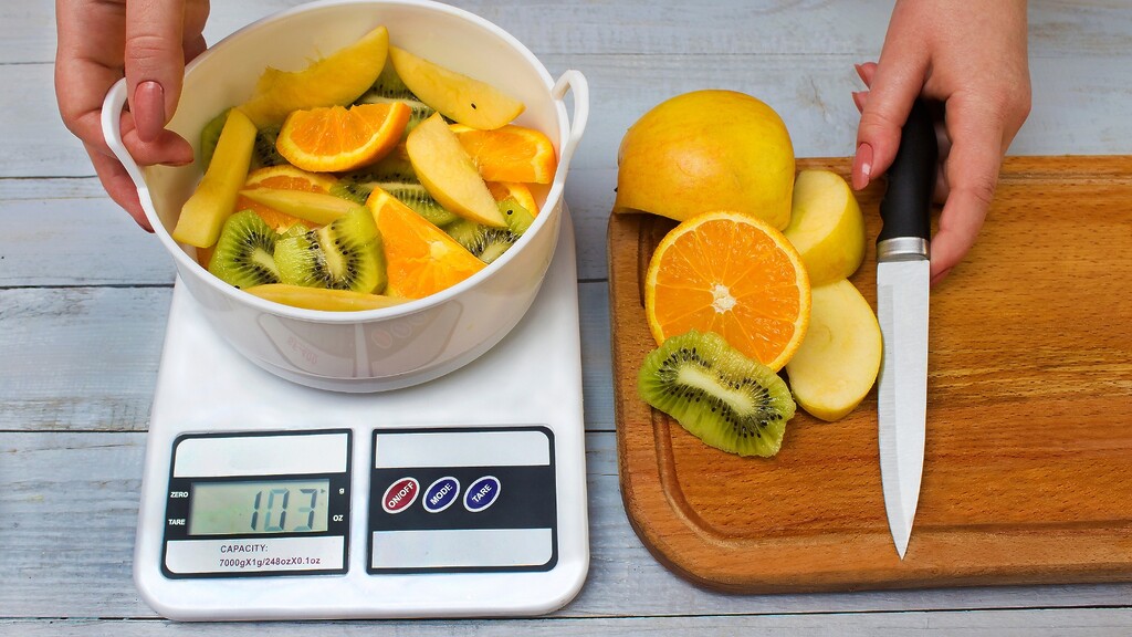 Bowl of fruit weighed on a digital food scale.