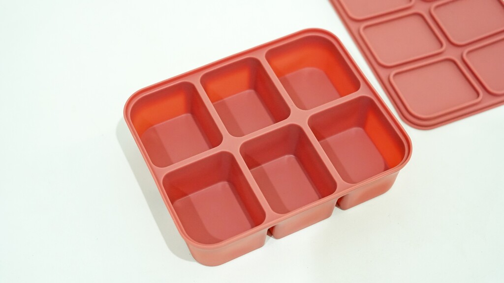 Red portion freezer tray with separate compartments.