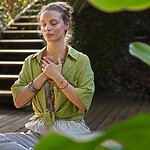 A Simple 4-Minute Meditation to Reset a Stressful Day Woman meditating outdoors with hands over her chest.