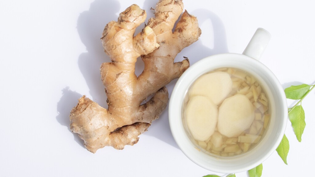 Fresh ginger root beside a cup of ginger tea.