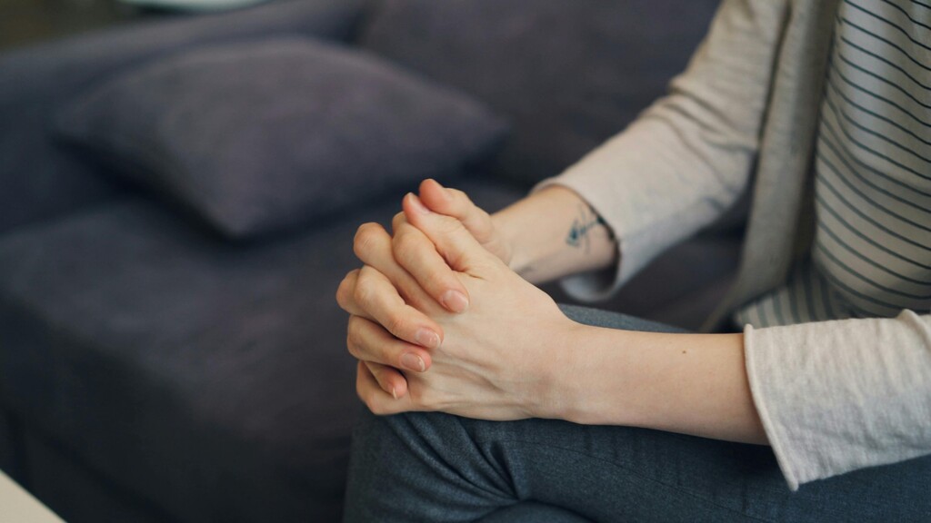 Close-up of clasped hands resting in a calm seated position.