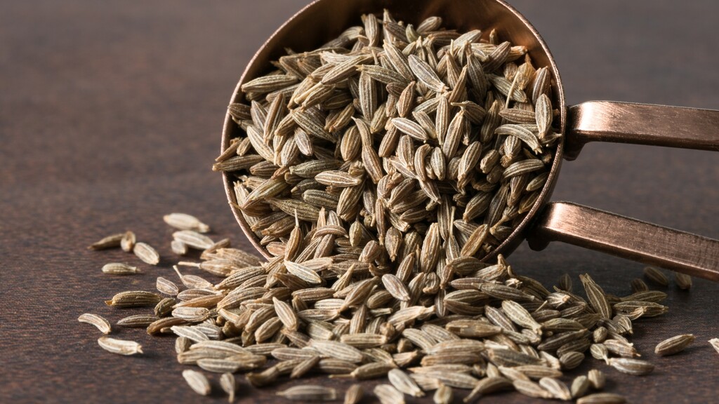 A rustic clay bowl filled with whole roasted cumin seeds