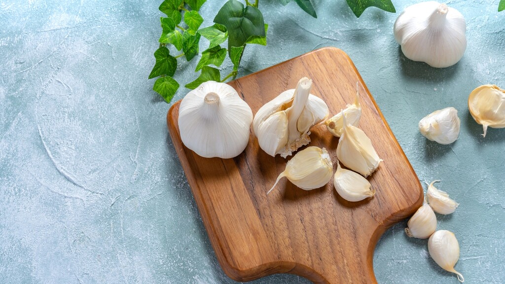 Garlic bulbs and cloves scattered on a wooden cutting board.
