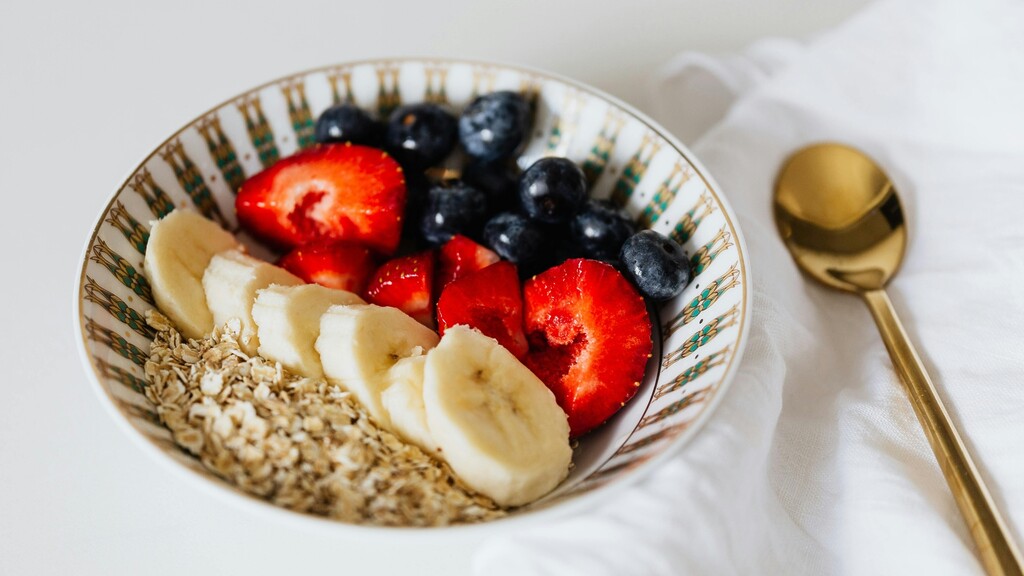 Bowl of oats topped with banana slices, strawberries, and blueberries.
