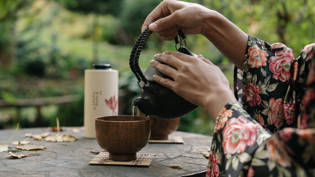Hands pouring hot water from a kettle into a mug
