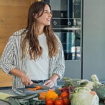 Keto vs. Low-Carb vs. Atkins: Choosing Your Right Fit Woman preparing fresh vegetables on a kitchen counter with assorted low-carb produce in the foreground.