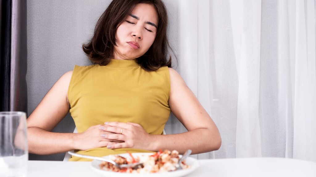 Woman holding her stomach after a meal.