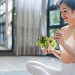 10 Low-Carb Diet Mistakes You Might Be Making (And How to Fix Them) Woman eating a salad after exercise in a bright studio.