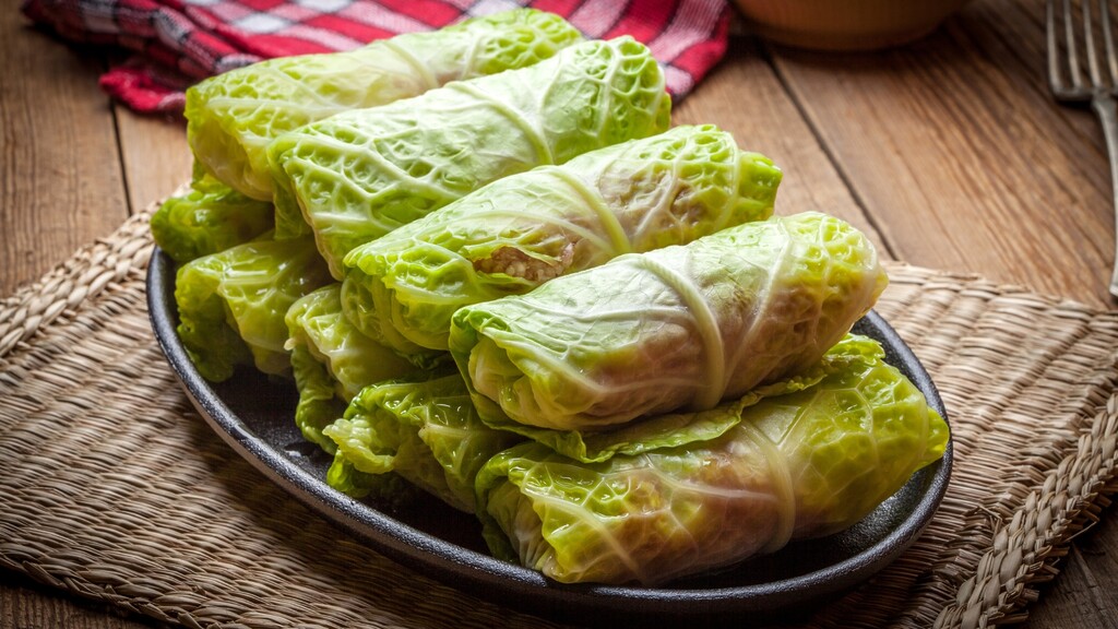 Stuffed cabbage rolls arranged on a dark plate.