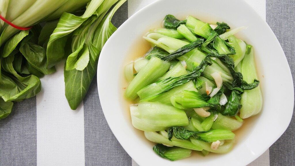 Stir-fried bok choy with garlic in a light sauce on a white plate.