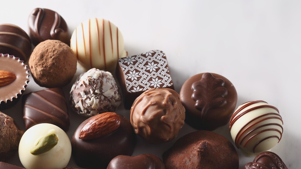Assorted chocolates and truffles arranged on a white background.