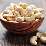 14 Sneaky High-Carb Foods to Avoid (And What to Eat Instead) Raw cashews in a wooden bowl on a rustic wooden table.