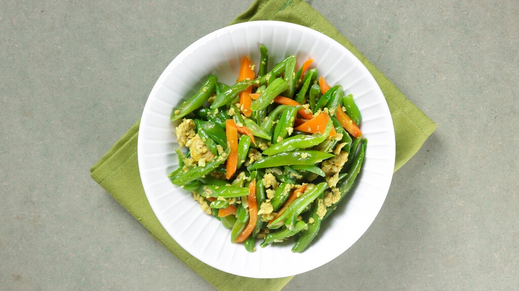 Green beans and carrot strips stir-fried with scrambled egg in a white bowl.