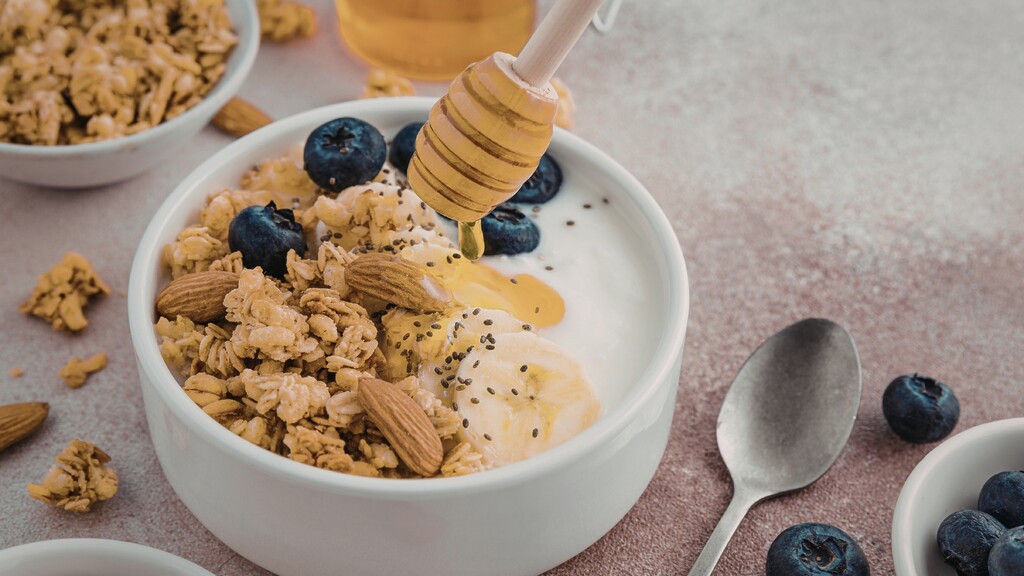 Yogurt bowl topped with granola, almonds, blueberries, chia seeds and honey.