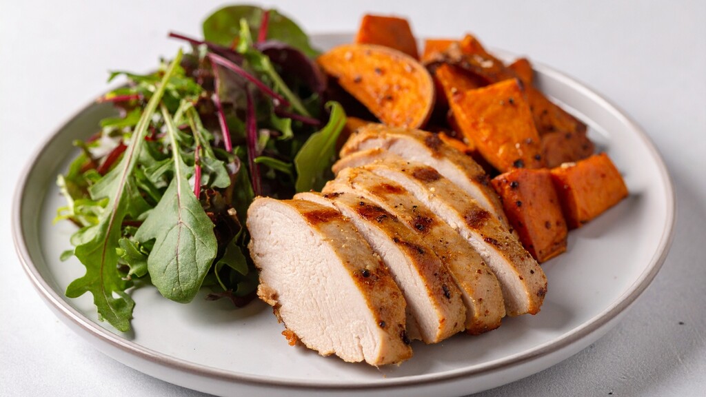 Balanced plate with sliced chicken, leafy greens, and roasted sweet potatoes for a protein- and fiber-rich meal.