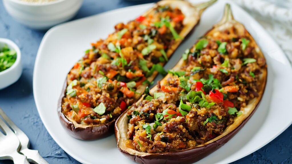 Baked stuffed eggplant halves filled with vegetables and grains, topped with herbs.