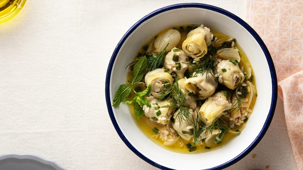 Artichoke hearts in olive oil with herbs served in a white bowl.