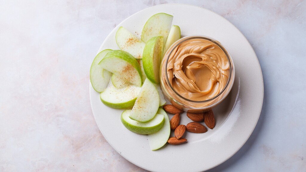 Apple slices served with peanut butter and almonds.