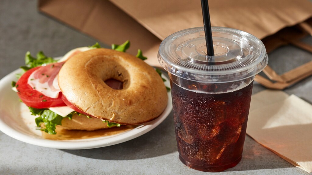 Bagel sandwich served with an iced drink.