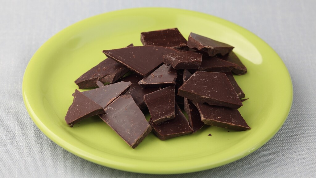 Dark chocolate pieces on a green plate.