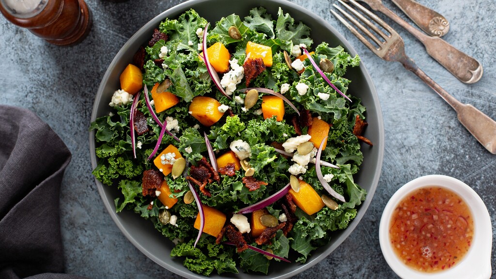 Kale salad with roasted squash, crumbled cheese, red onion, pumpkin seeds, and dressing.