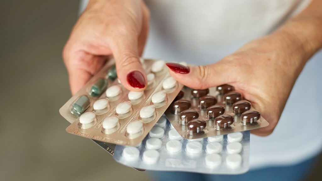 Hands holding several blister packs of pills.