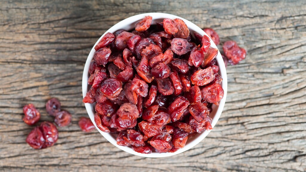 Bowl of dried cranberries on a rustic wooden surface.