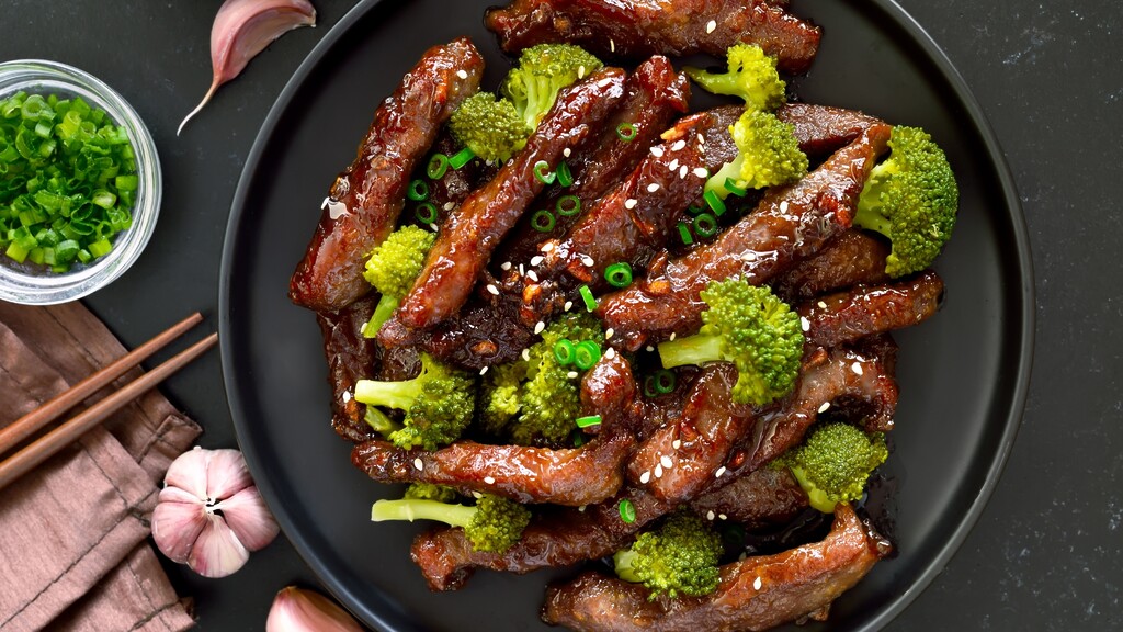 Glazed beef and broccoli stir-fry topped with sesame seeds and sliced green onions.
