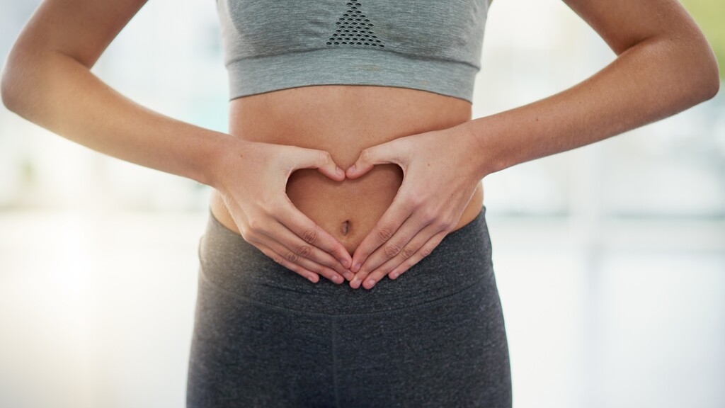 Person forming a heart shape with their hands over their stomach, symbolizing gut health and digestive care.