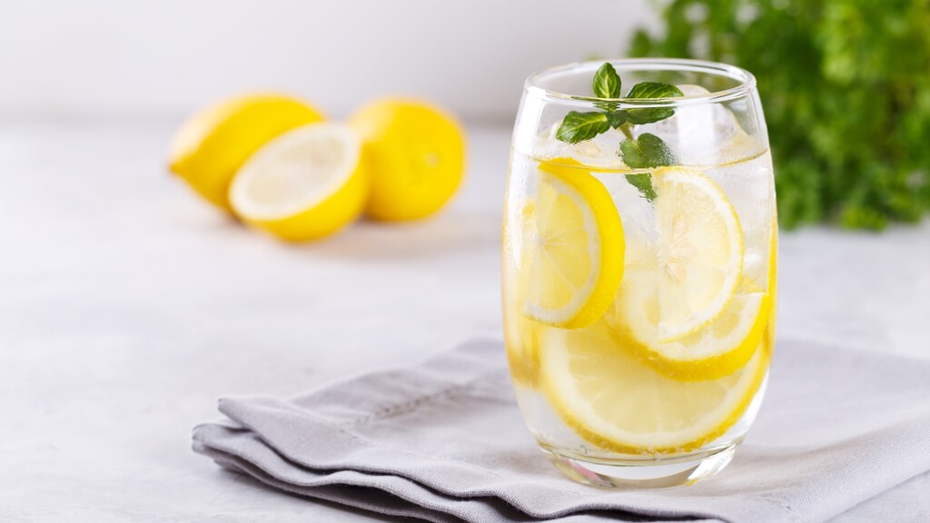 Glass of lemon water with fresh mint, representing simple hydration for healthier-looking skin.
