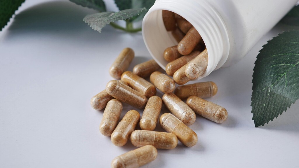 Probiotic capsules spilling from a white bottle.