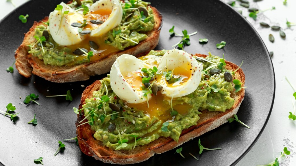 Avocado toast topped with soft-boiled eggs and microgreens.