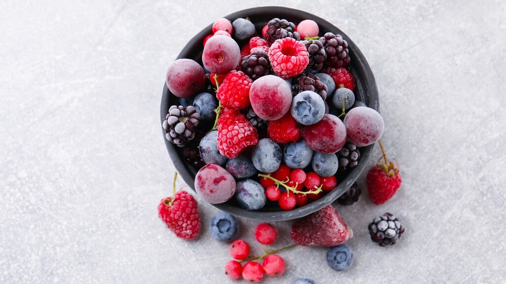 A black bowl filled with fresh strawberries, blueberries, and blackberries