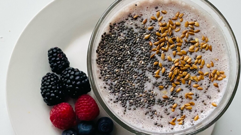 A smoothie bowl topped with chia seeds, flaxseeds, and mixed berries.