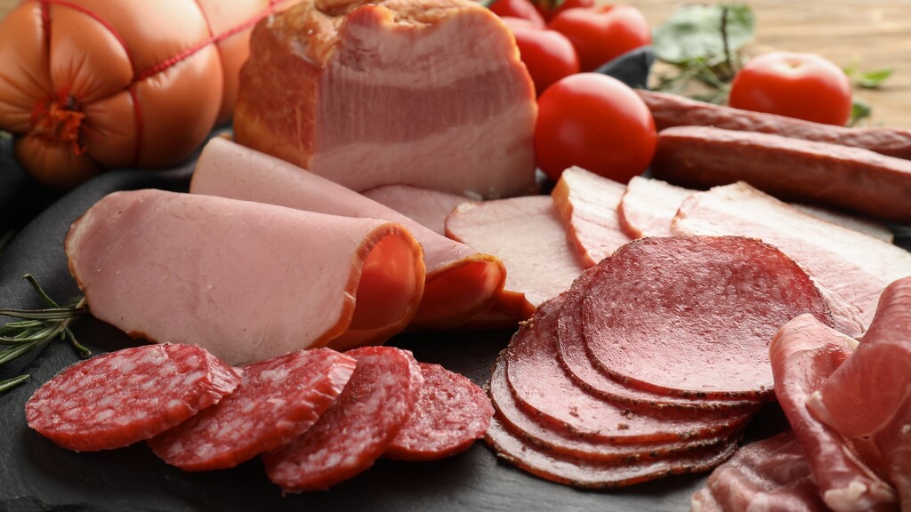 Assorted processed meats, including deli slices, sausages, and salami.
