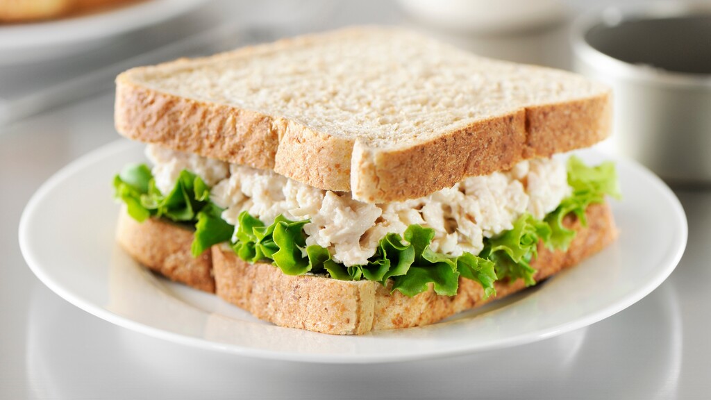 A white bread sandwich with lettuce and a creamy filling on a plate.