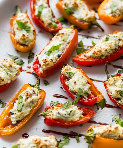 Colorful mini sweet pepper halves filled with a creamy feta, basil, and garlic blend, arranged on parchment