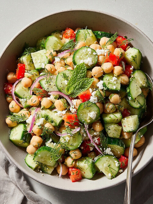 Mediterranean Chickpea Salad - the finished salad served in a bowl with a spoon, showing the creamy dressing coating the chickpeas and vegetables