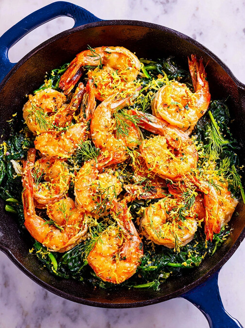 DASH Friendly Lemon Garlic Shrimp Recipe: Pre-serving stage in the skillet, showing seared shrimp mixed with spinach, topped with lemon zest and herbs before being transferred to a plate.