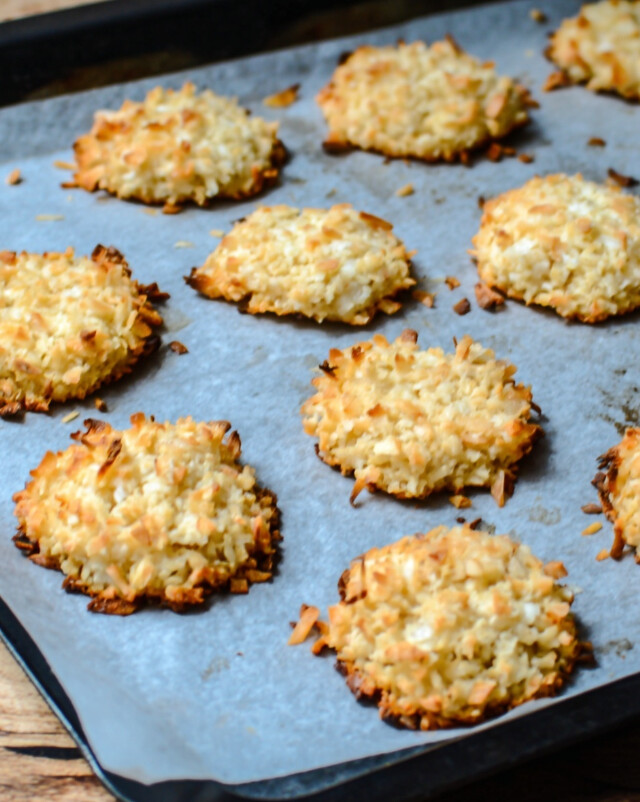 Keto Almond Cookies - Freshly baked golden rounds cooling on a parchment-lined baking sheet, showing crisp edges.