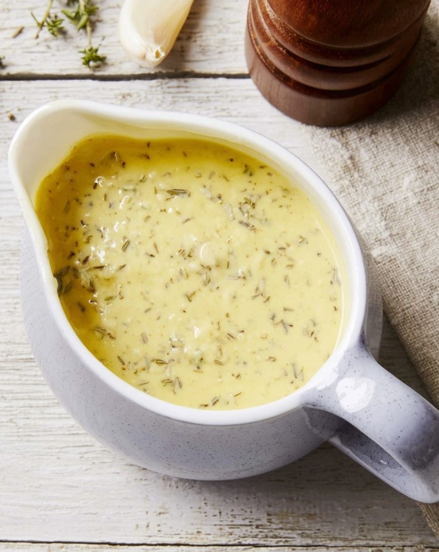 Creamy garlic and herb sauce ready and strained for serving inside a sauce bowl